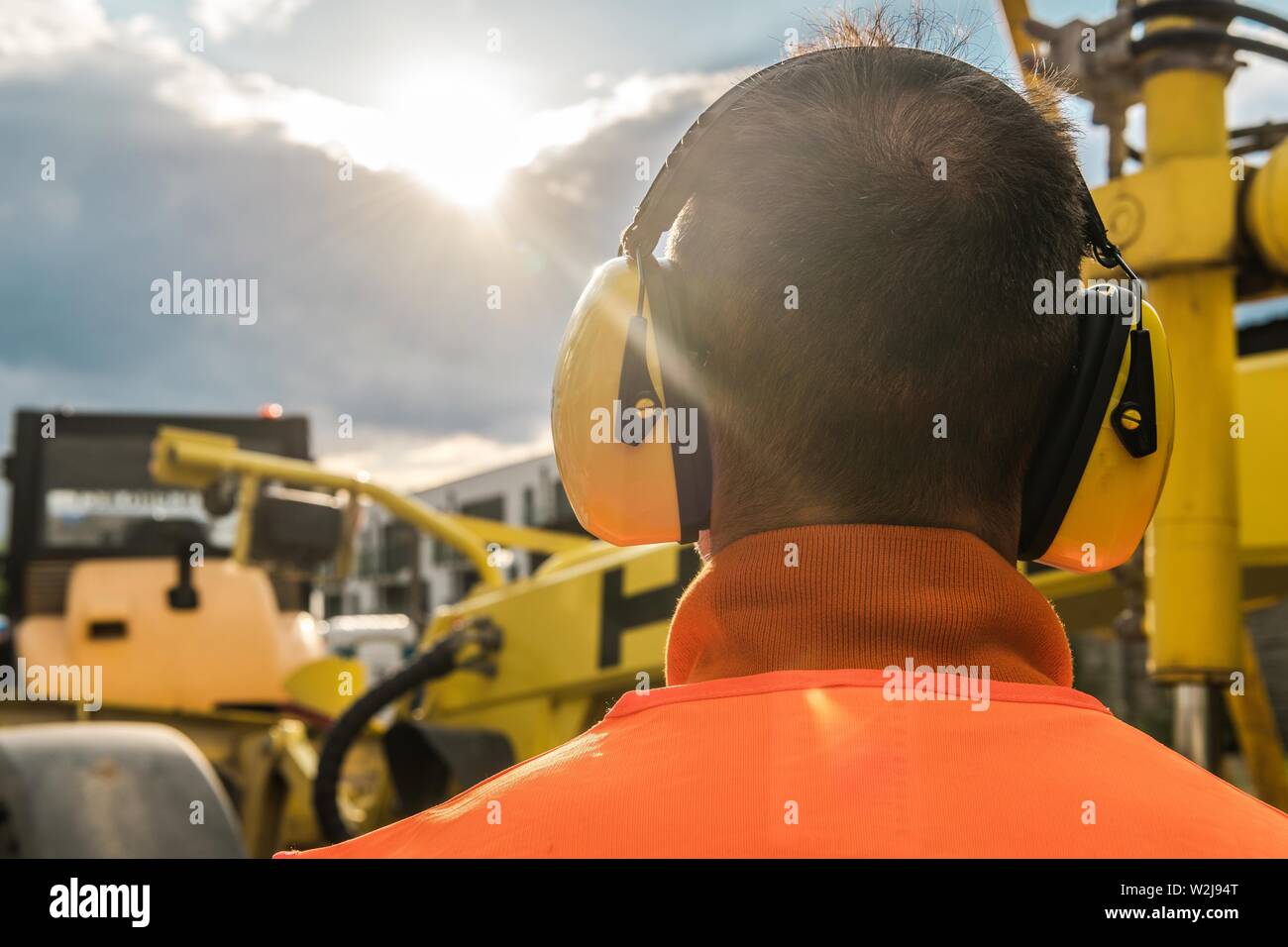 Noise Reduction Construction Equipment. Caucasian Worker with Hearing Protection Headphones. Stock Photo