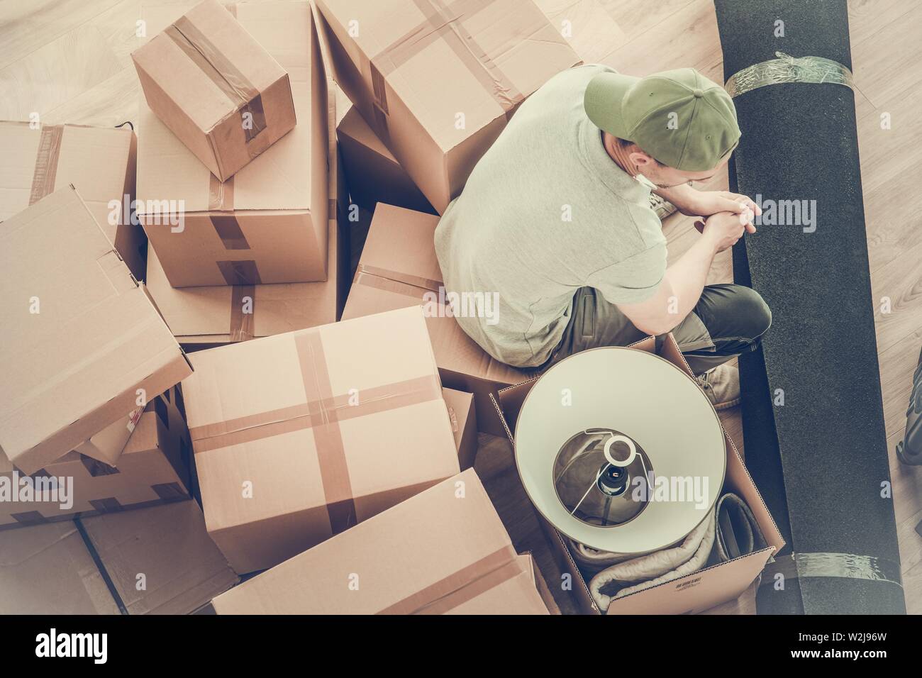 Caucasian Men Moving Out After Divorce. Seating on a Boxes with His Staff Awaiting Moving Company. Stock Photo
