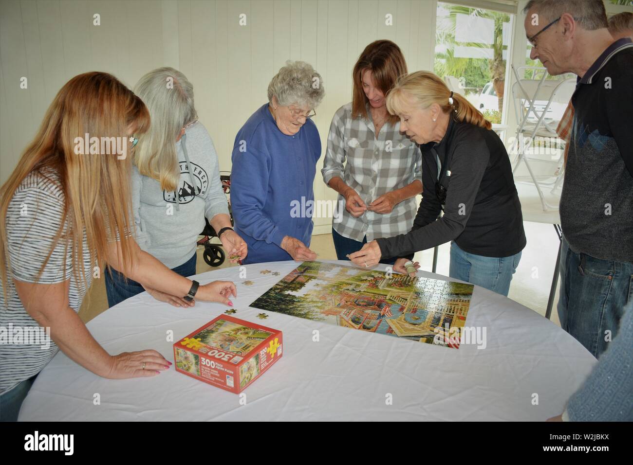 Women from real family at gathering doing crossword puzzle - Mother at 90 and 2 daughters and in laws at barbecue having fun together Stock Photo
