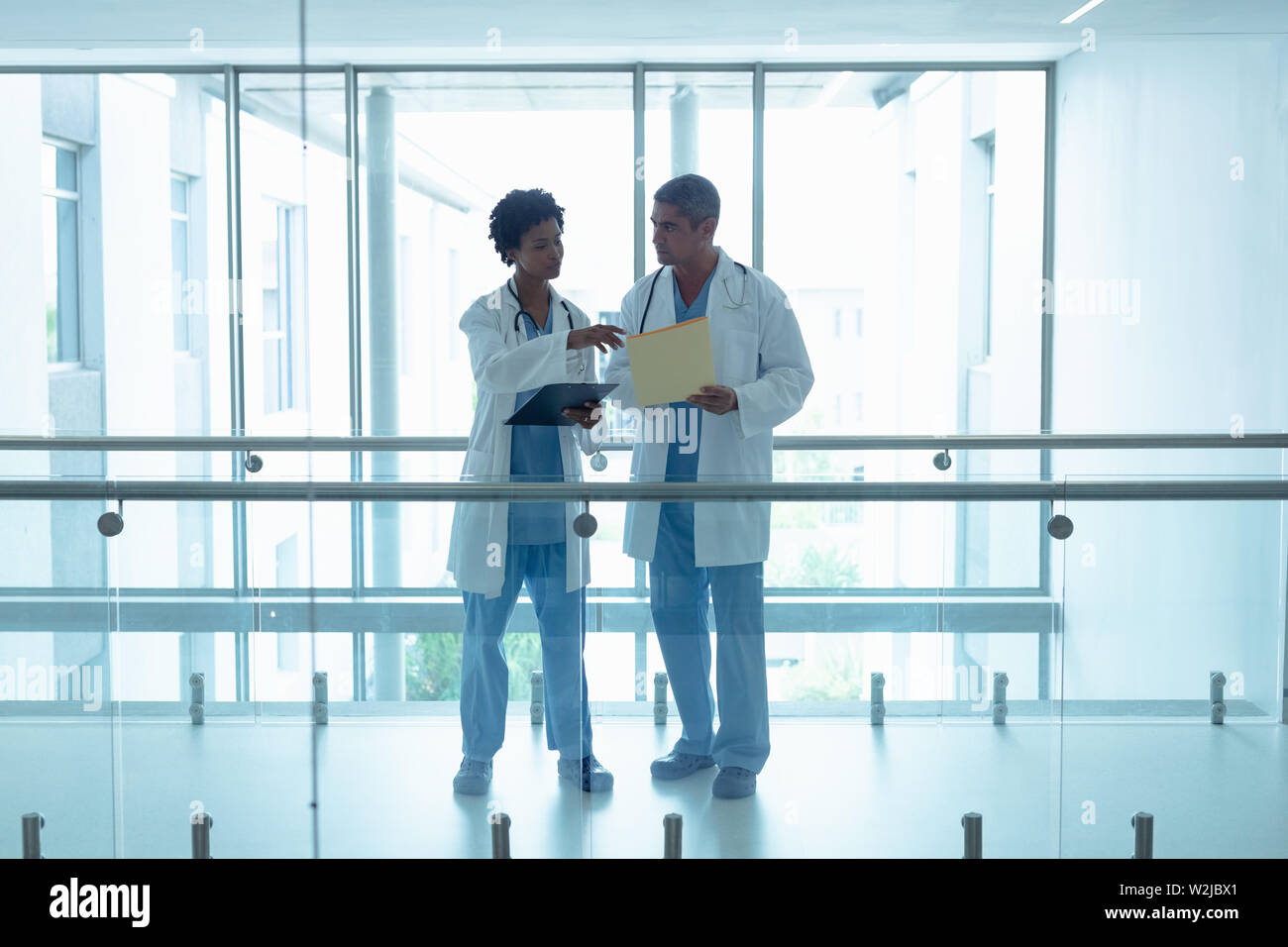 Male and female doctors interacting with each other in the corridor ...