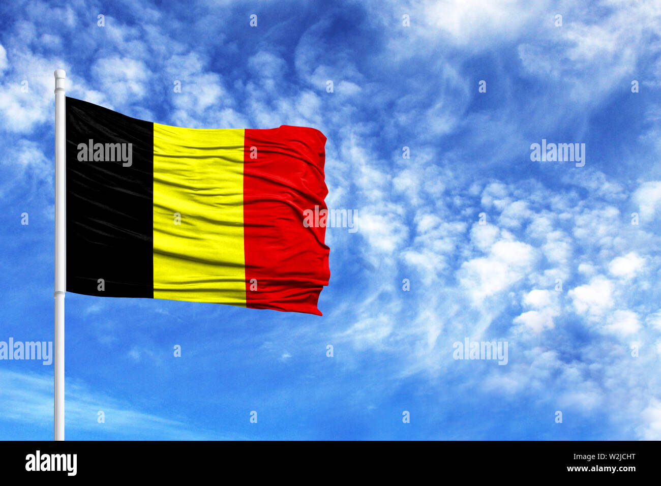 National flag of Belgium on a flagpole in front of blue sky Stock Photo