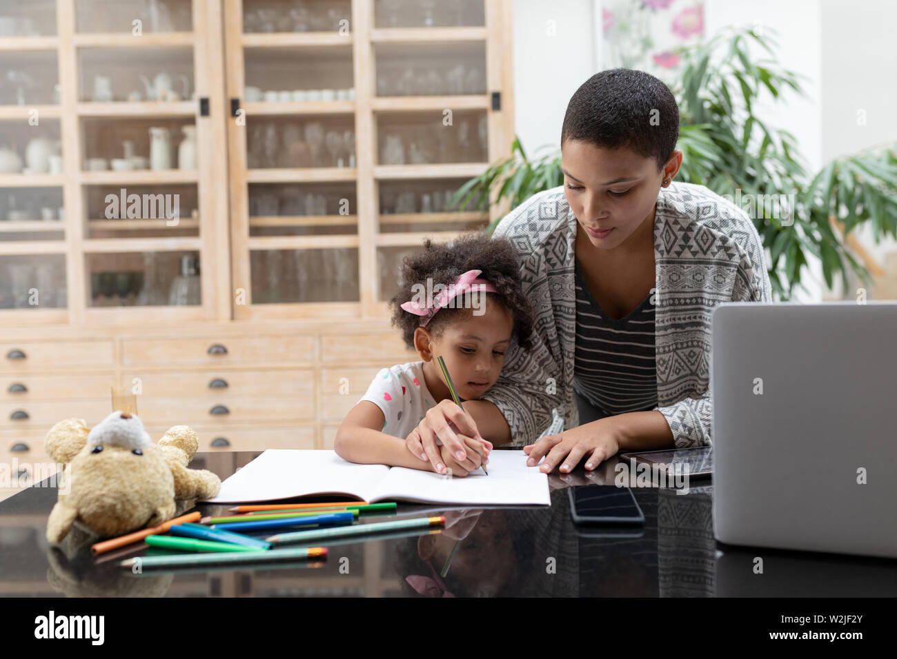 Mother helping her daughter with her homework on a table Stock Photo ...
