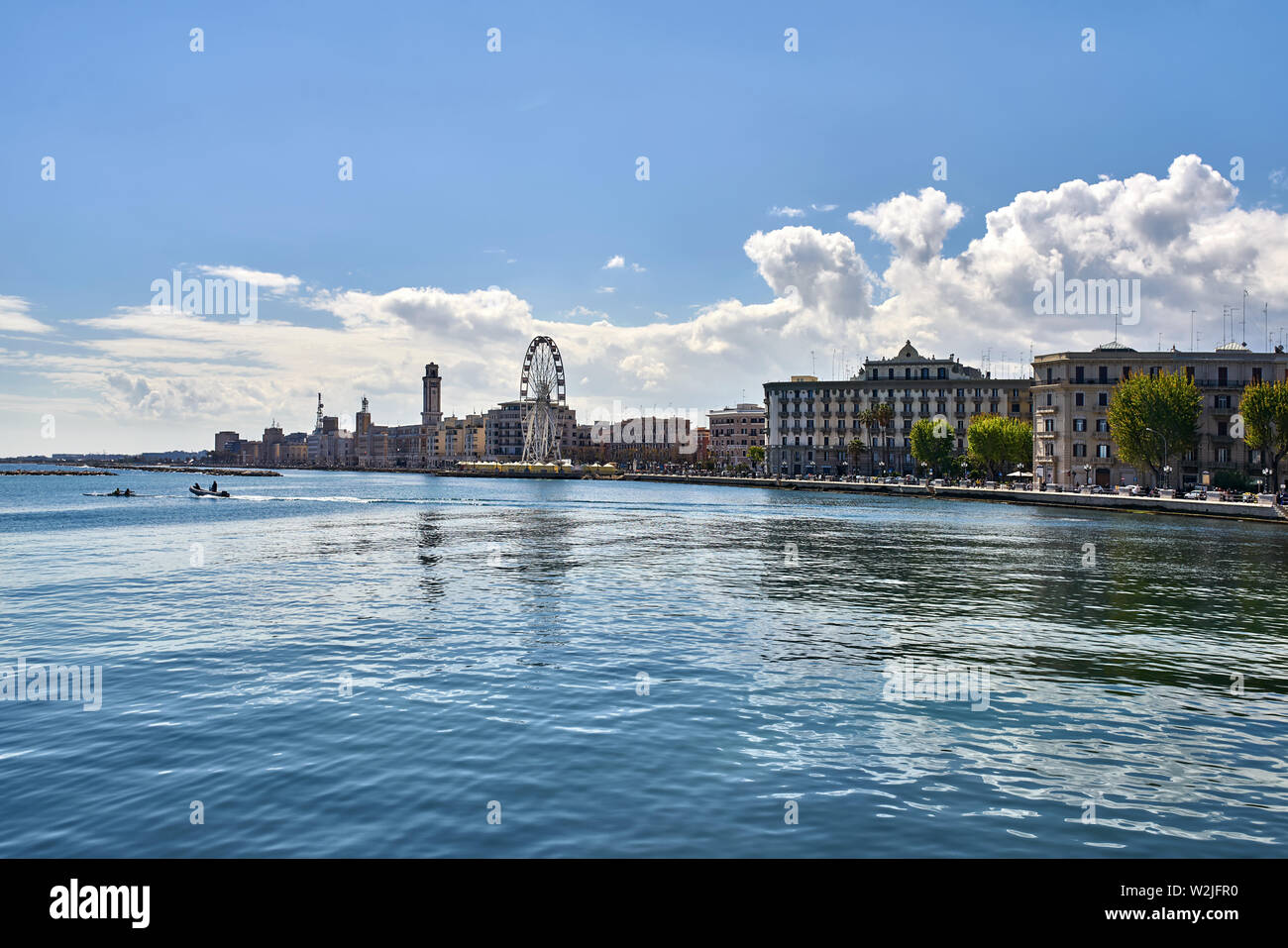 Panoramic cityscape of an embankment on the background of the blue sky with white clouds in Bari port city on Adriatic Coast in Italy. There is a ferr Stock Photo