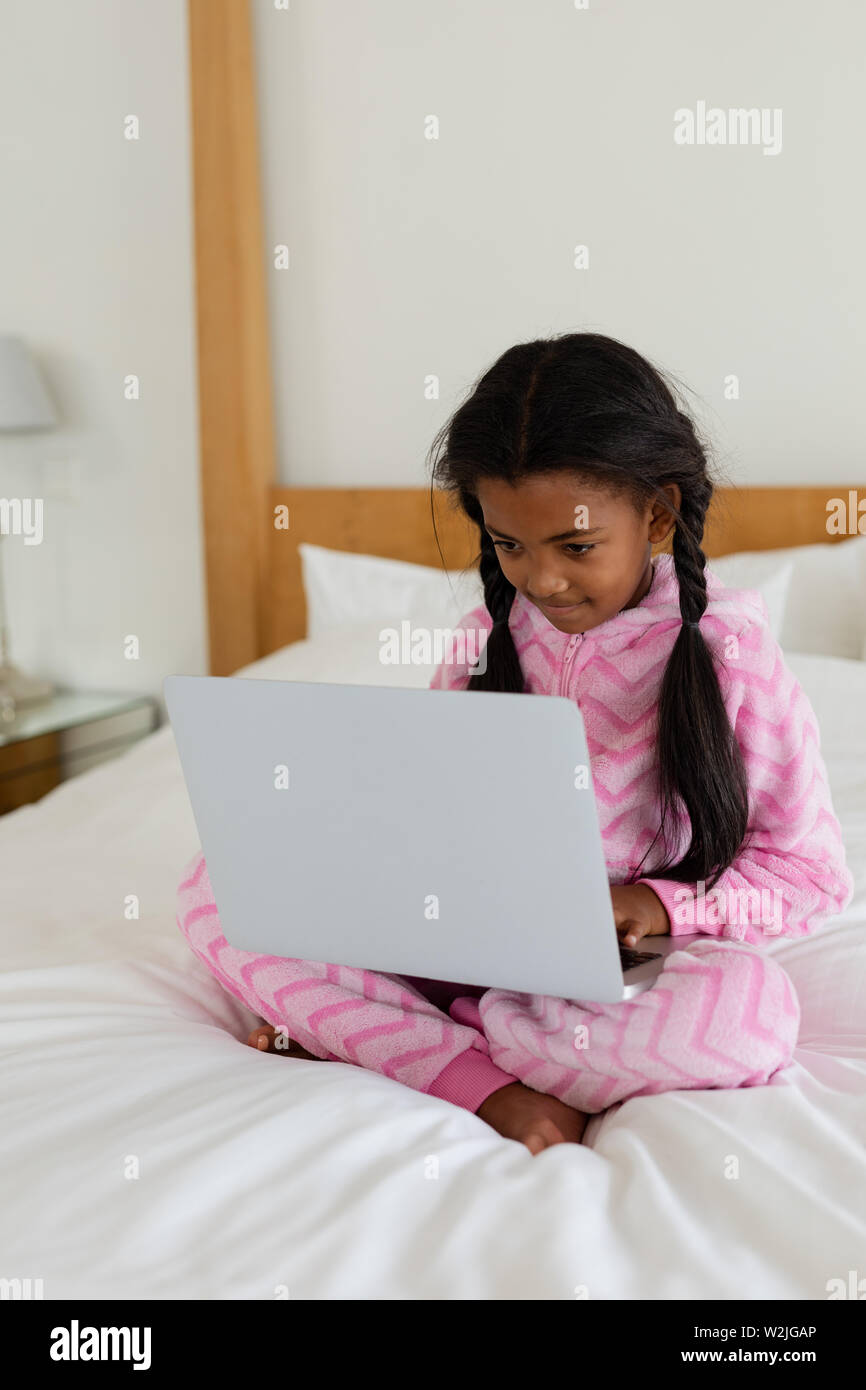 Girl using laptop on bed in bedroom at home Stock Photo
