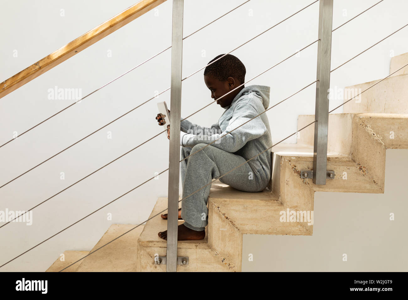 Boy using digital tablet on staircase at home Stock Photo
