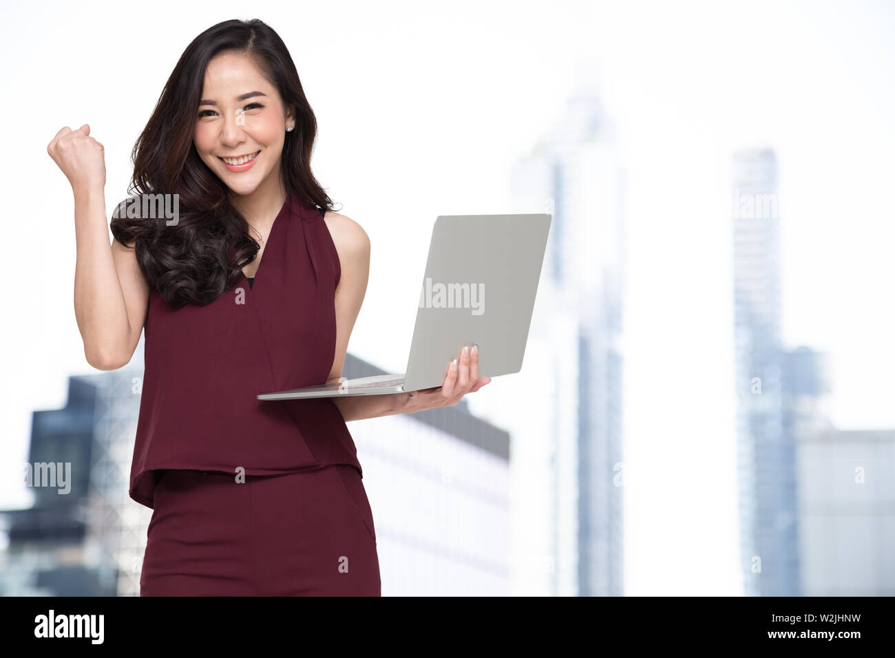 Portrait of an excited Asian woman holding laptop computer and ...