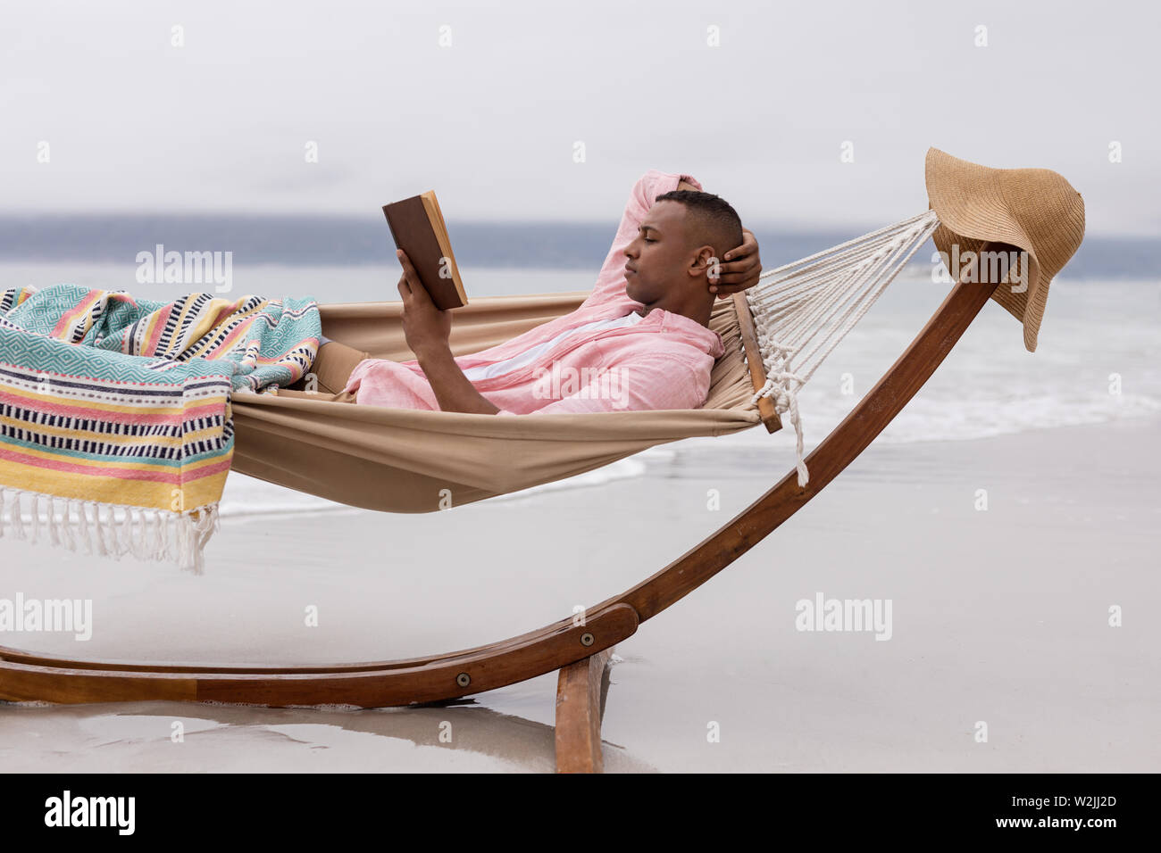 Man reading a book while relaxing on a hammock at beach Stock Photo - Alamy