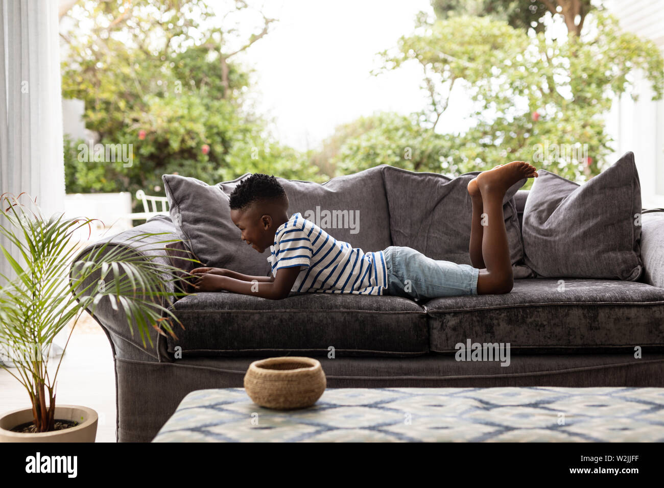 Boy using digital tablet on a sofa in living room Stock Photo