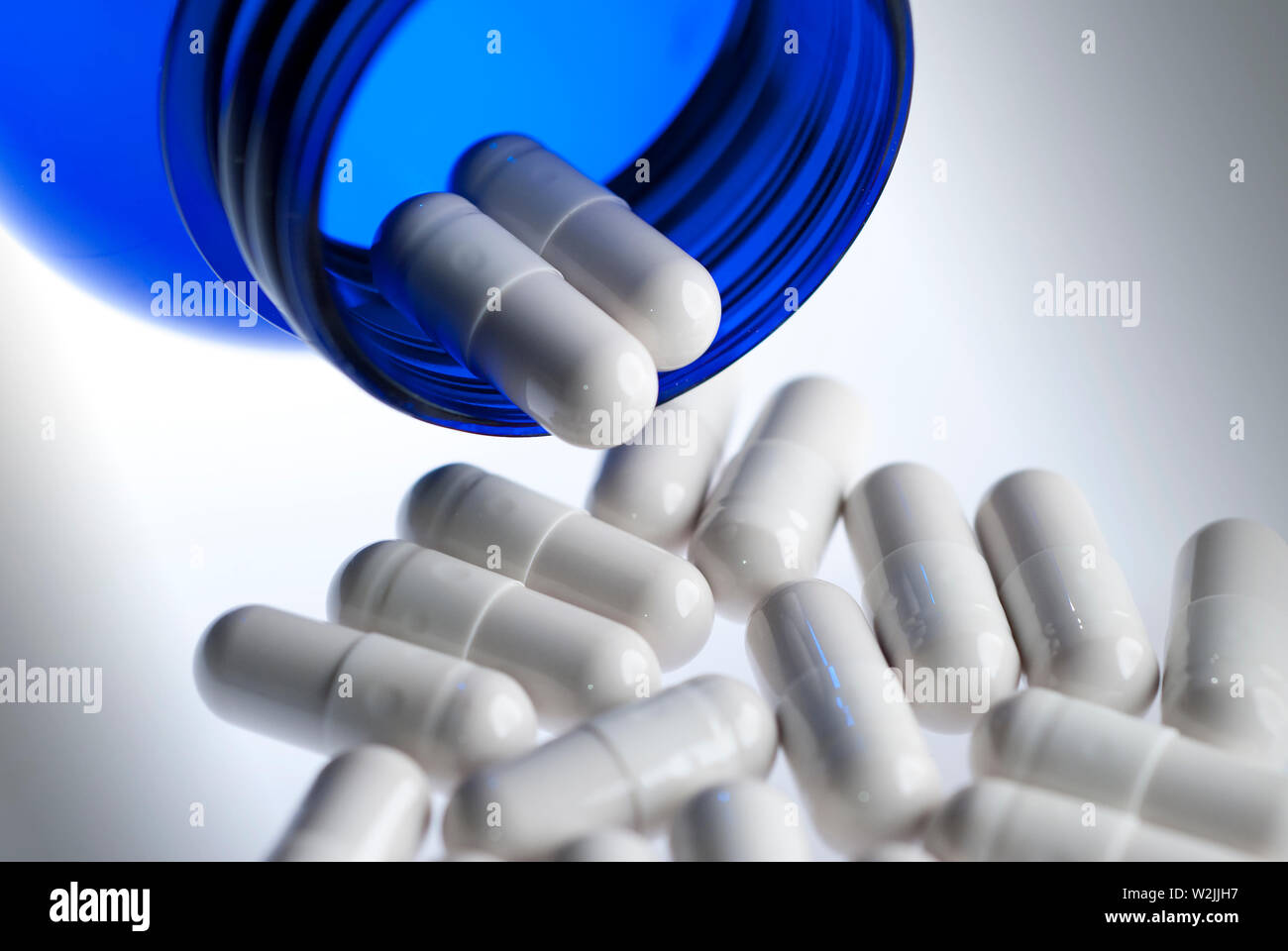 Medical pills spilling out of a blue bottle Stock Photo