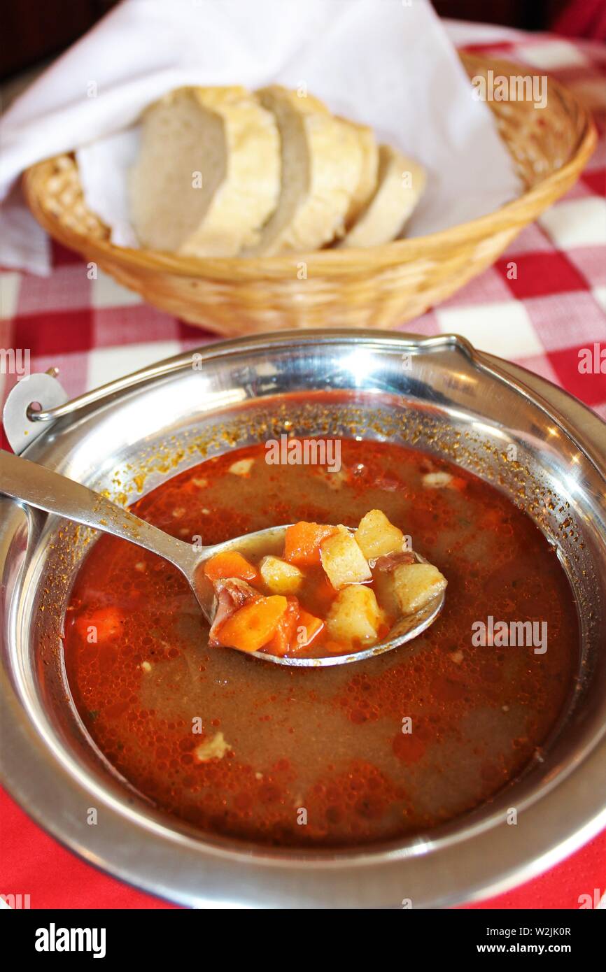 A bowl of traditional Hungarian Goulash soup with a basket of bread. Goulash is the national dish of Hungary. Stock Photo
