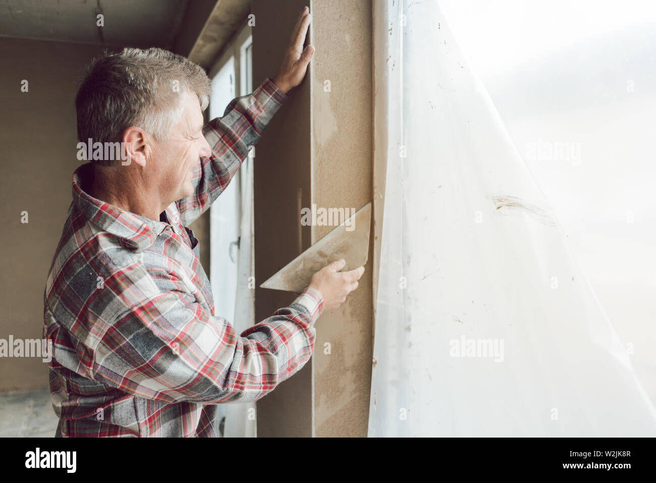 Diligent plasterer working on a window opening Stock Photo