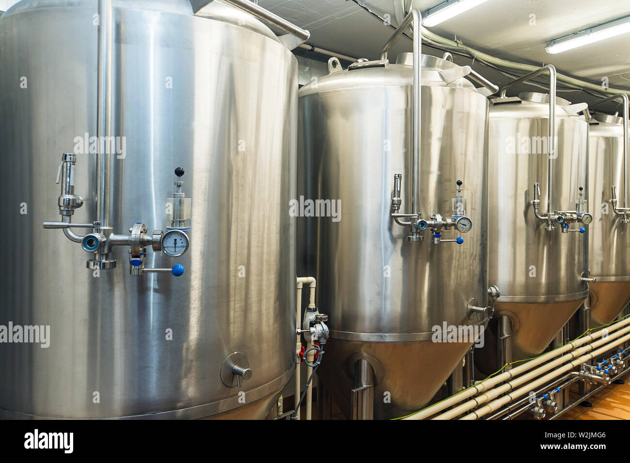 Lines of metal tanks in modern brewery. Shopfloor with brewery facilities. Manufacturable process of brewage. Mode of beer production. Industry Stock Photo