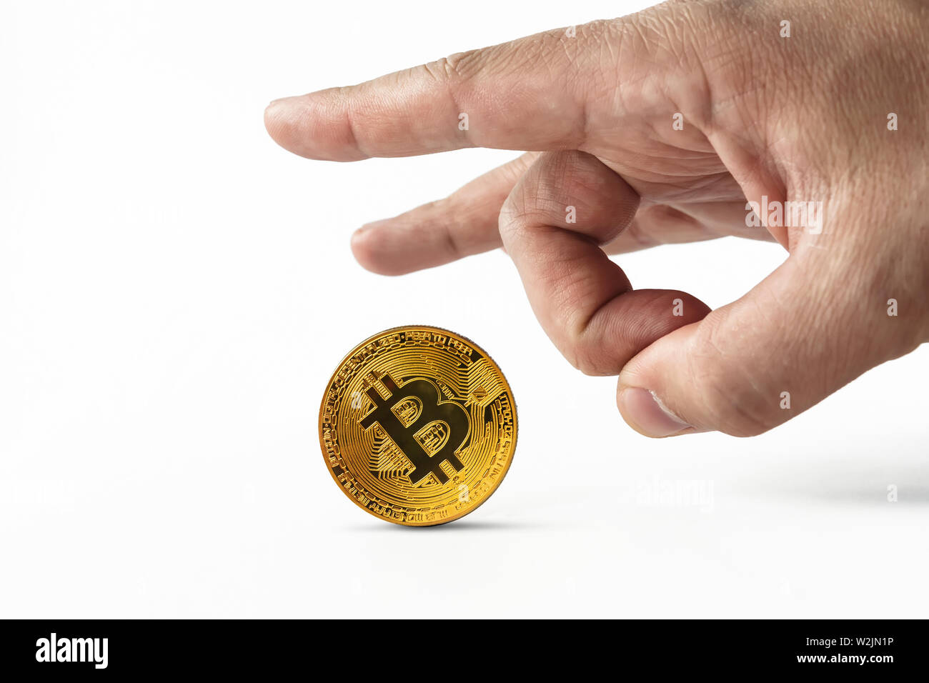 Man put bitcoin on edge and pulls it away kicking with index finger. Depreciation of virtual money bitcoin. Concept of depreciation of cryptocurrency Stock Photo