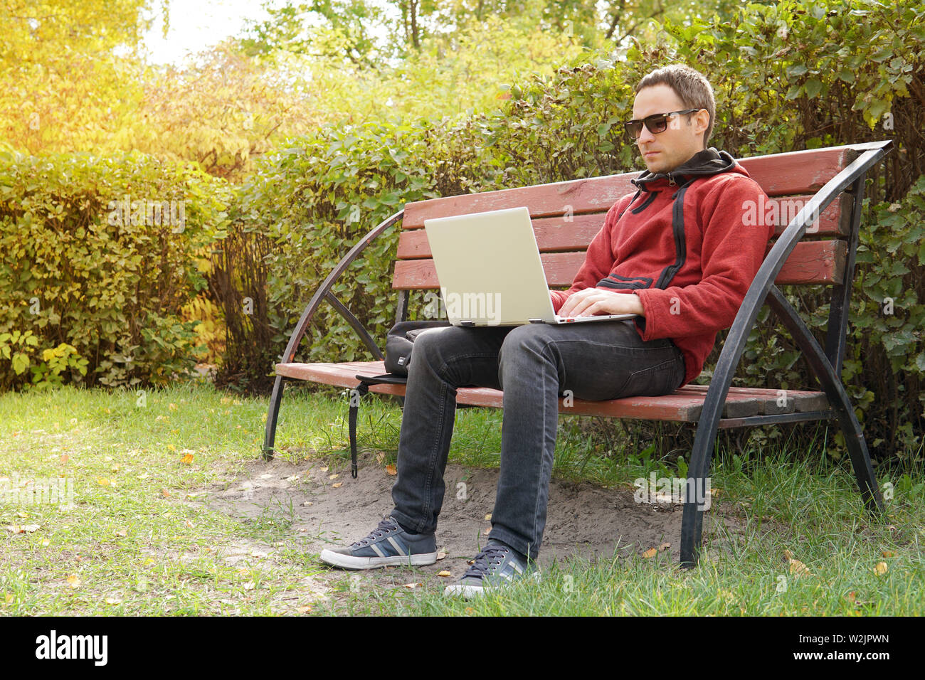 Young man working on his laptop connect to wireless internet in rural area. Internet connection allows people to work anywhere. Freelancer programmer Stock Photo