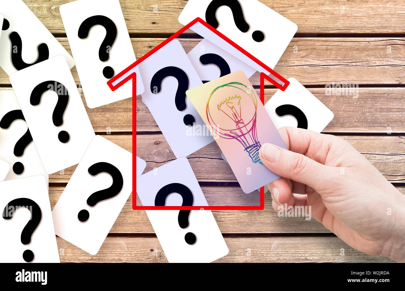 The solution to doubts, questions and uncertainties about buildings - concept image with hand holding a card with light bulb Stock Photo