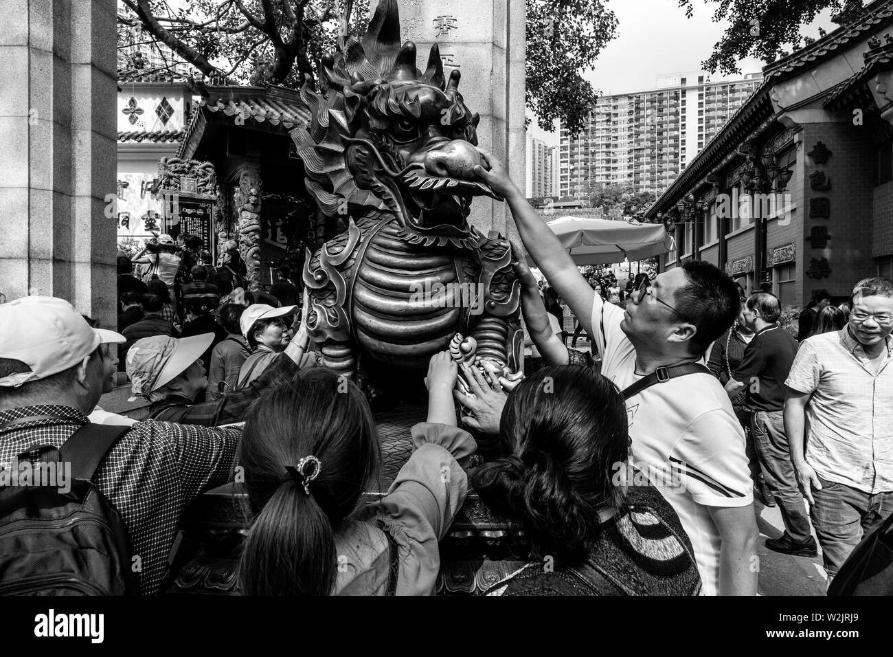 Chinese Tourists Rub The Dragon Statue For Good Luck At The Entrance To