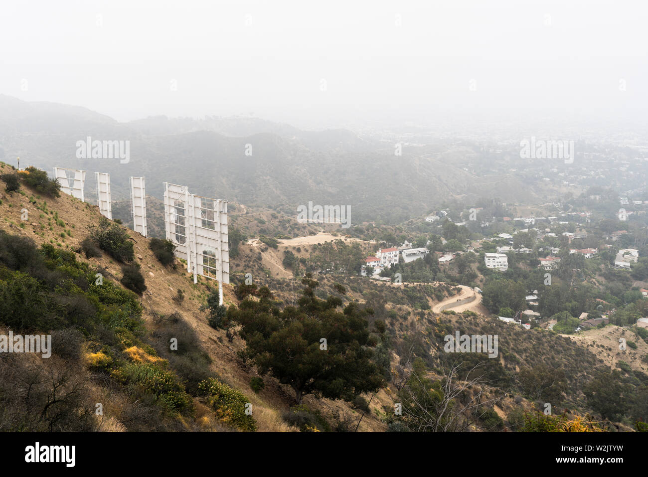 Los Angeles, California, USA - July 7, 2019:  Foggy morning view of the famous Hollywood Sign and hillside homes near popular Griffith Park. Stock Photo