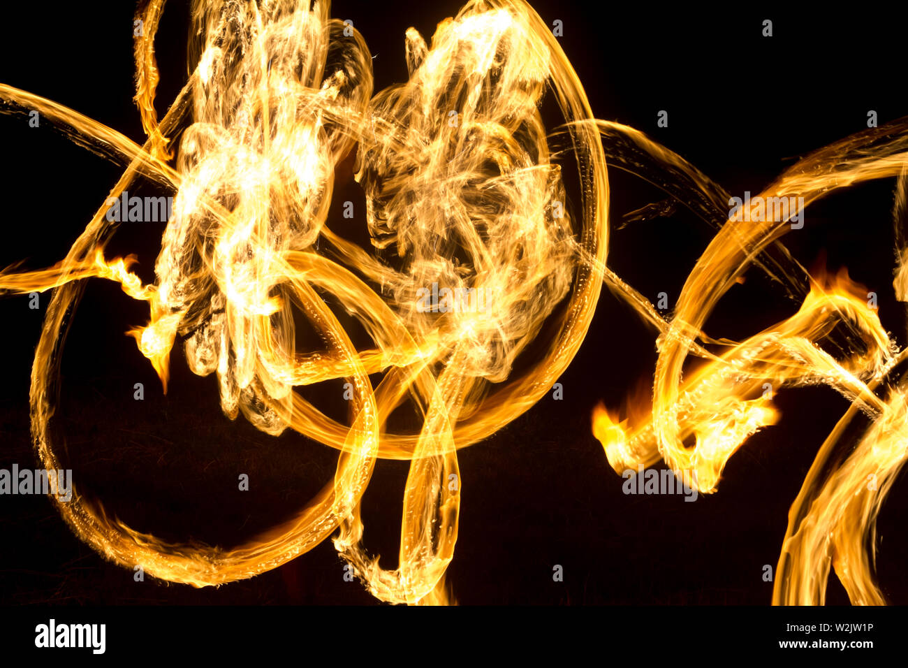 An artist shows a fire show at night spinning torches, circles of fire ...