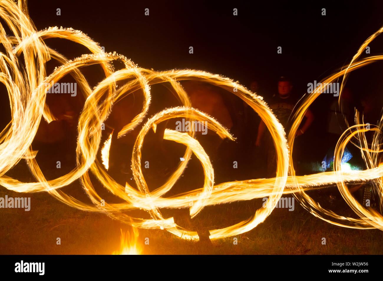 An artist shows a fire show at night spinning torches, circles of fire ...