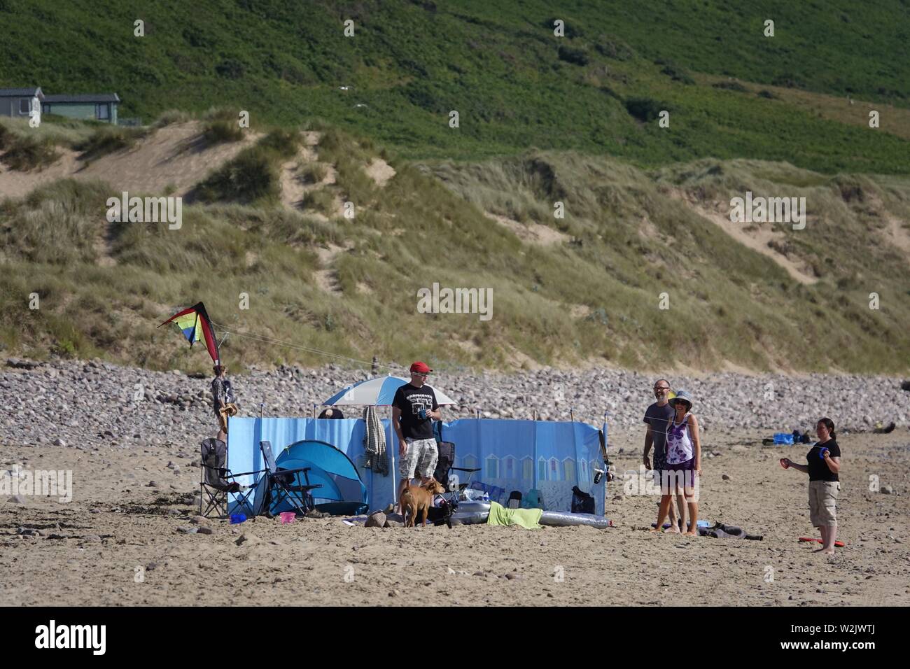 Gower, Swansea, Wales, UK. 9th July 2019. Weather: Beachgoers enjoy warm sunny weather with a cooling westerly breeze at Llangennith beach on the Gower coast, south Wales. The outlook is dry and bright with some cloud gathering but staying generally fine with more sunshine toward the weekend. Credit: Gareth Llewelyn/Alamy Live News Stock Photo