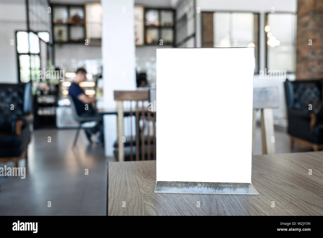 Blank screen mock up menu frame standing on wood table in coffee cafe and restaurant background with people. Stock Photo