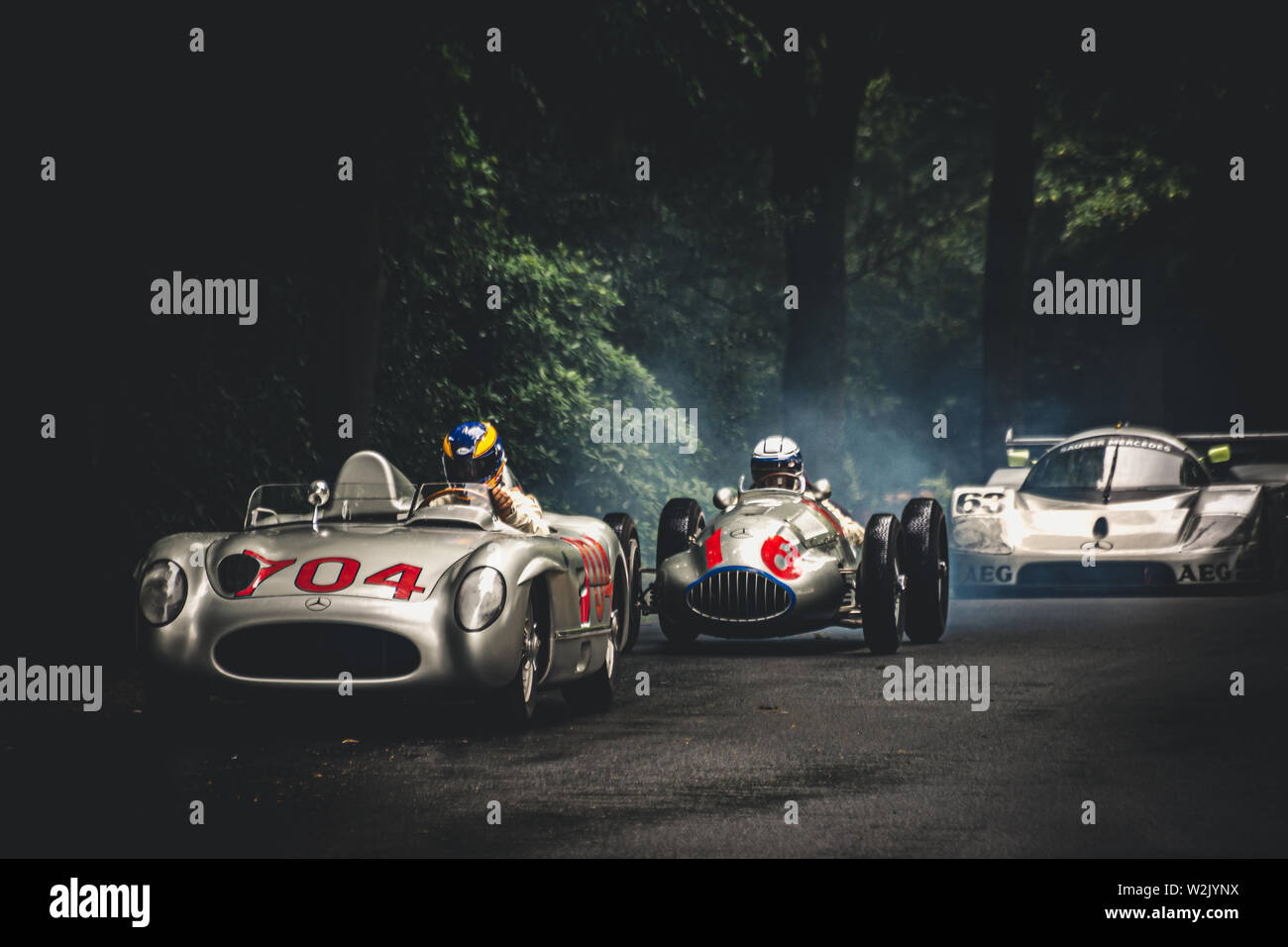 A line up of three classic and vintage Mercedes Benz racing and sports cars at Goodwood Festival of Speed 2019 in the dark shadow of the trees Stock Photo