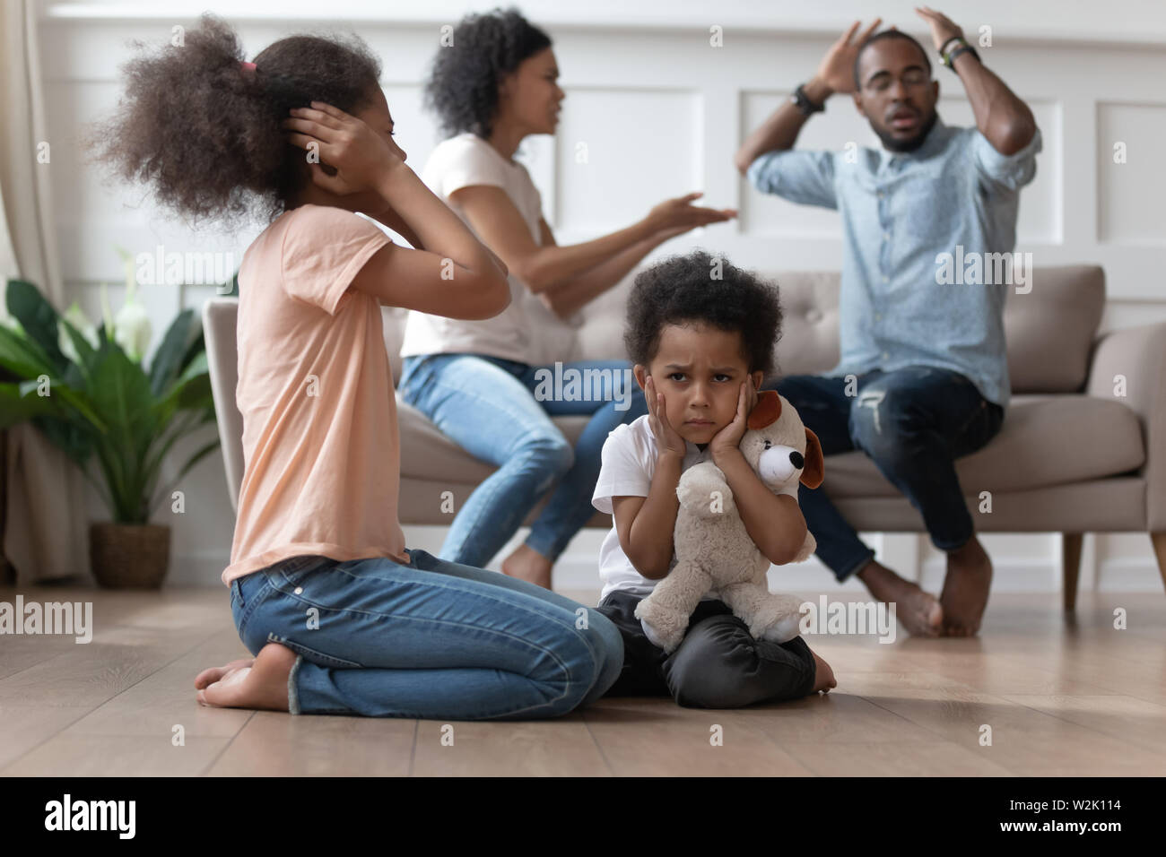 Upset african kids closing ears hurt by parents fighting Stock Photo