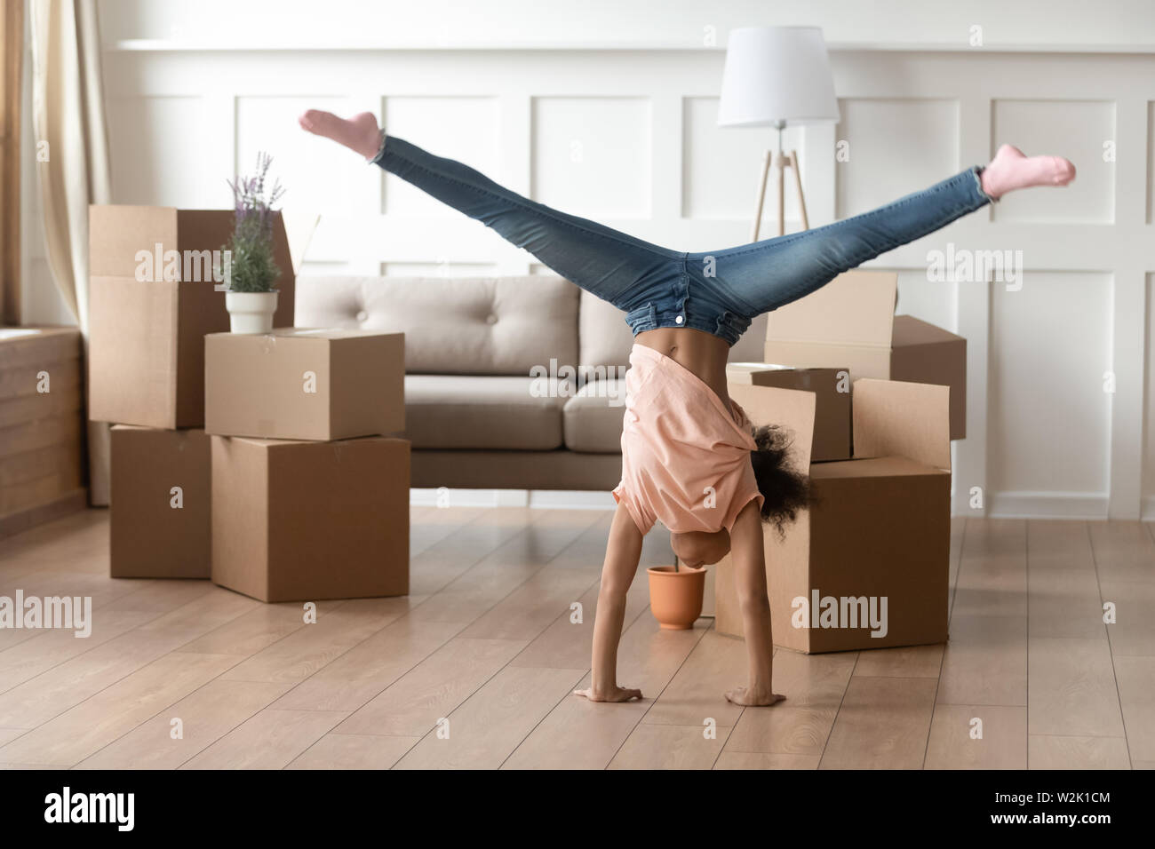 African kid doing cartwheel in living room on moving day Stock Photo