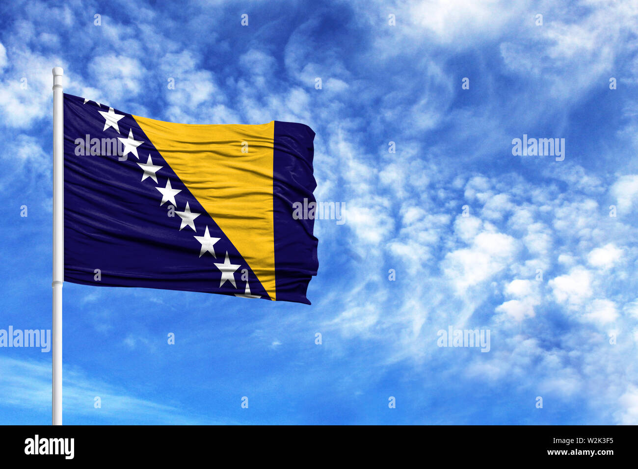 National flag of Bosnia and Herzegovina on a flagpole in front of blue ...