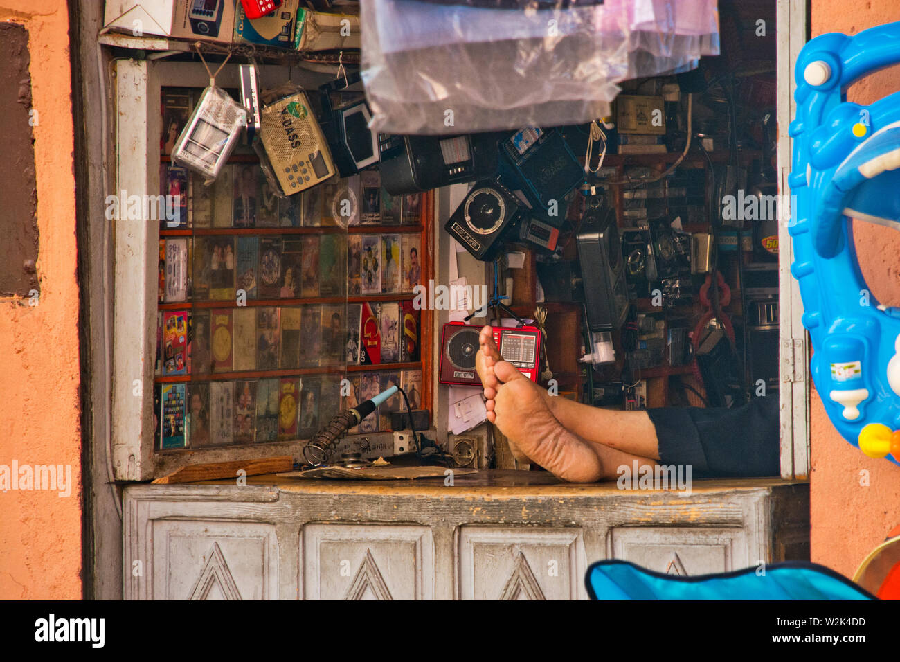 Relaxed local moroccan salesman resting feet on shopfront table asleep in Marakech Morocco Stock Photo