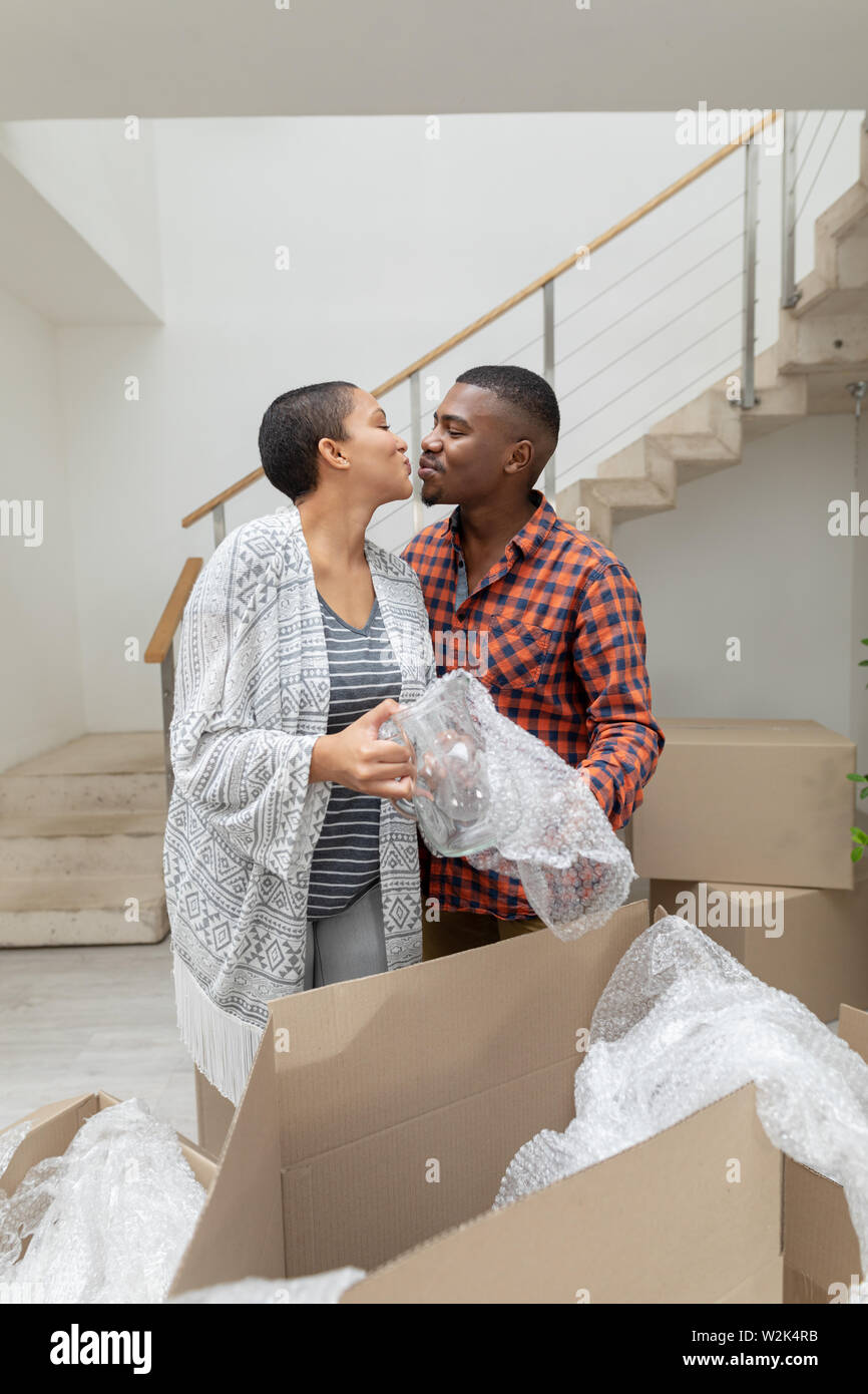 Couple kissing each other while unpacking cardboard boxes in living room Stock Photo