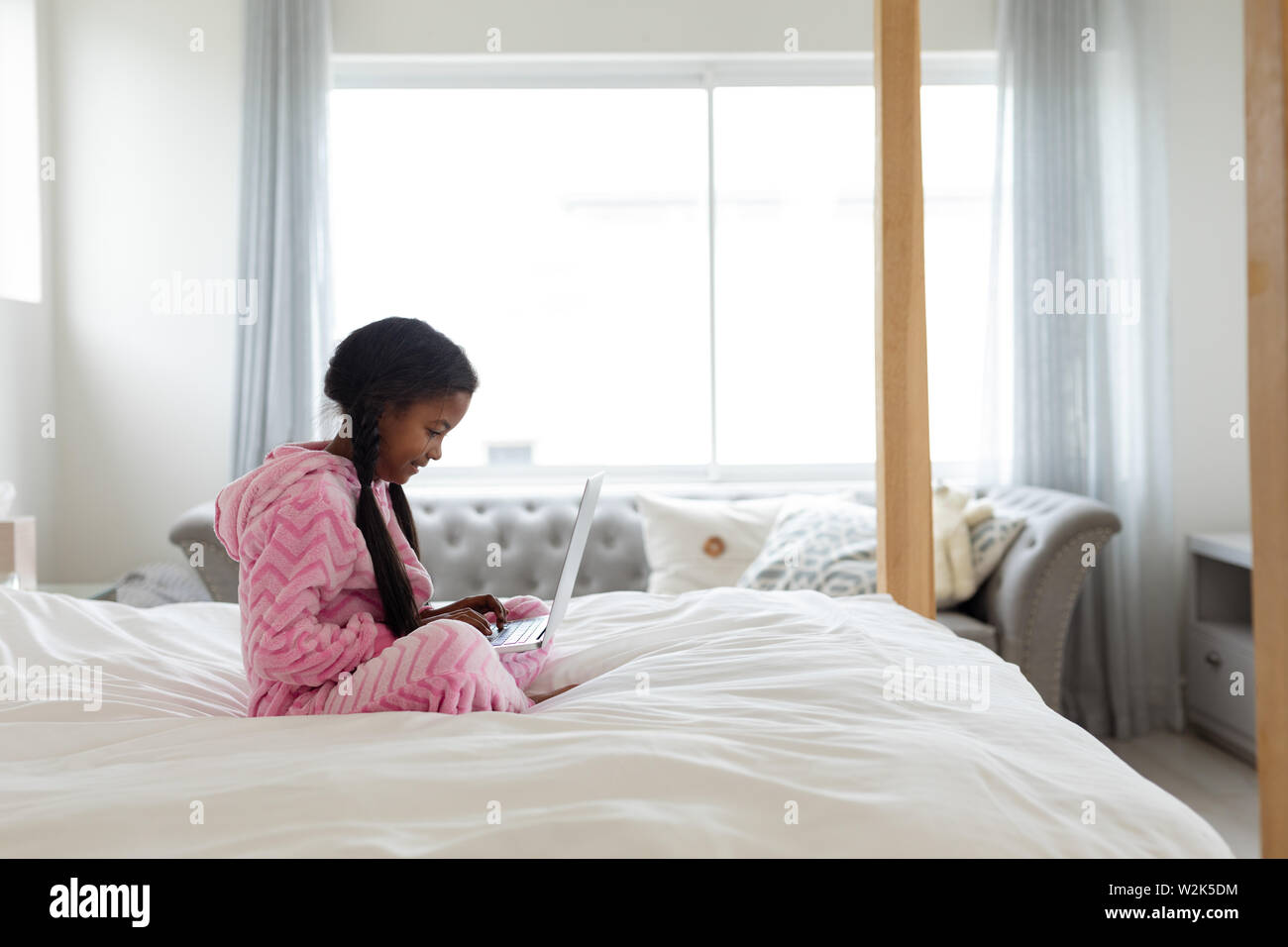 Girl using laptop on bed in bedroom at home Stock Photo