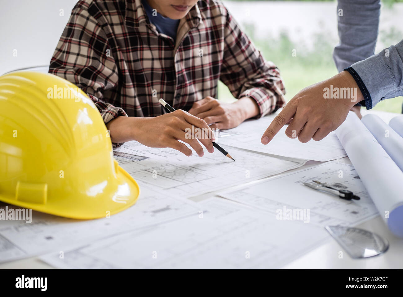 Construction engineering or architect discuss a blueprint while checking information on drawing and sketching meeting for architectural project in wor Stock Photo