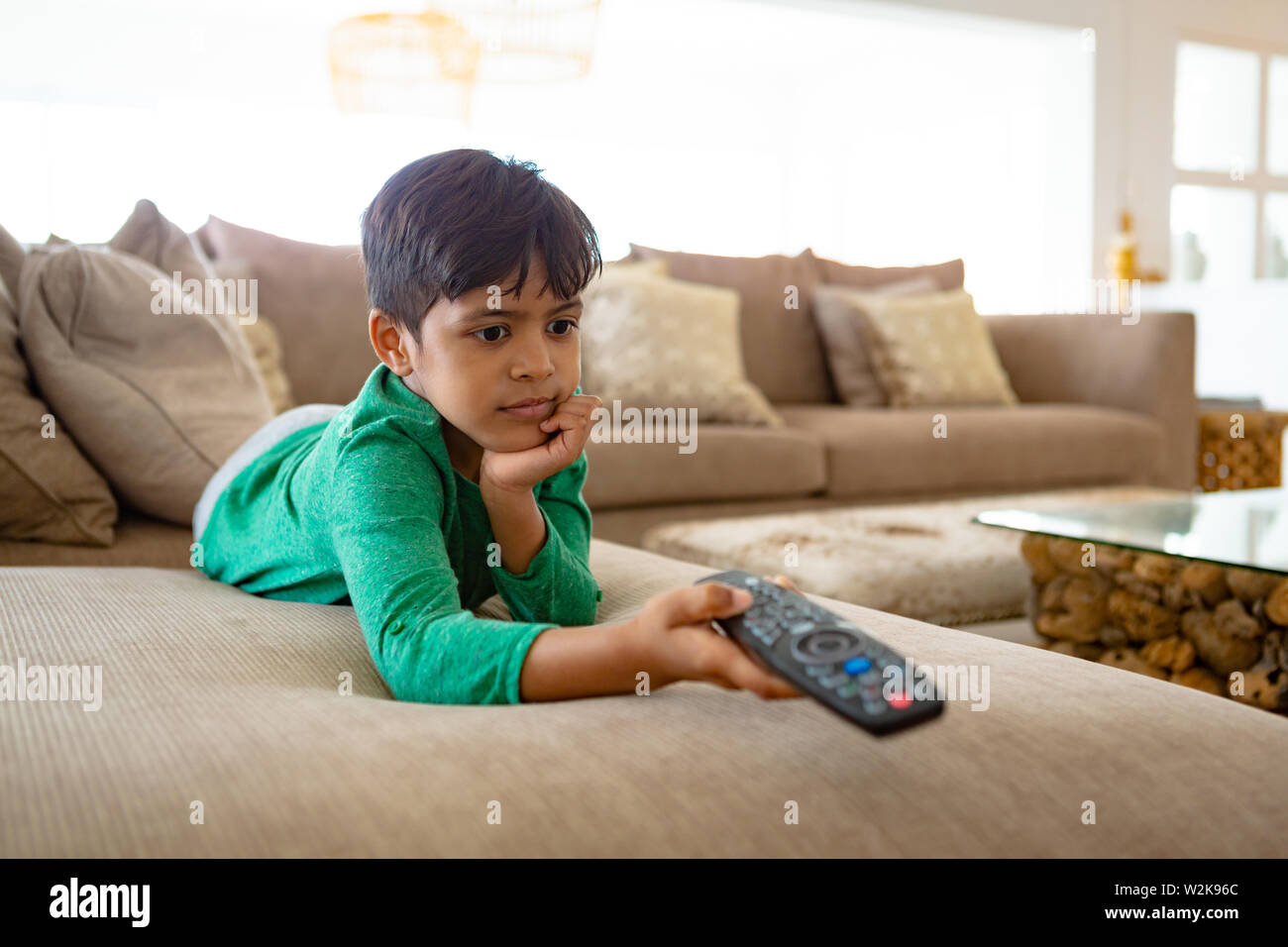 Boy watching television while lying on sofa at home Stock Photo