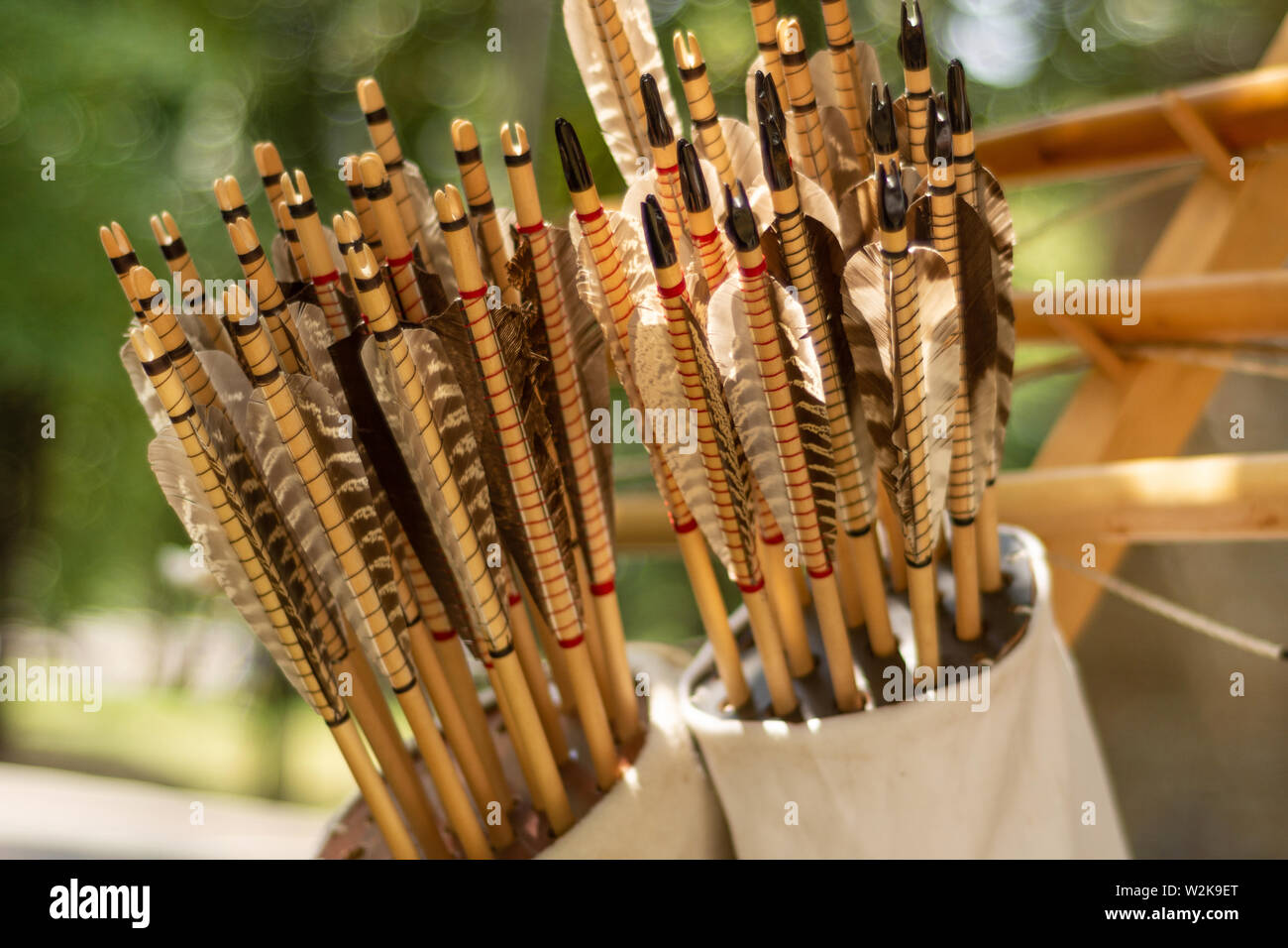 Many handcrafted arrows in a brown leather quiver full with arrows in