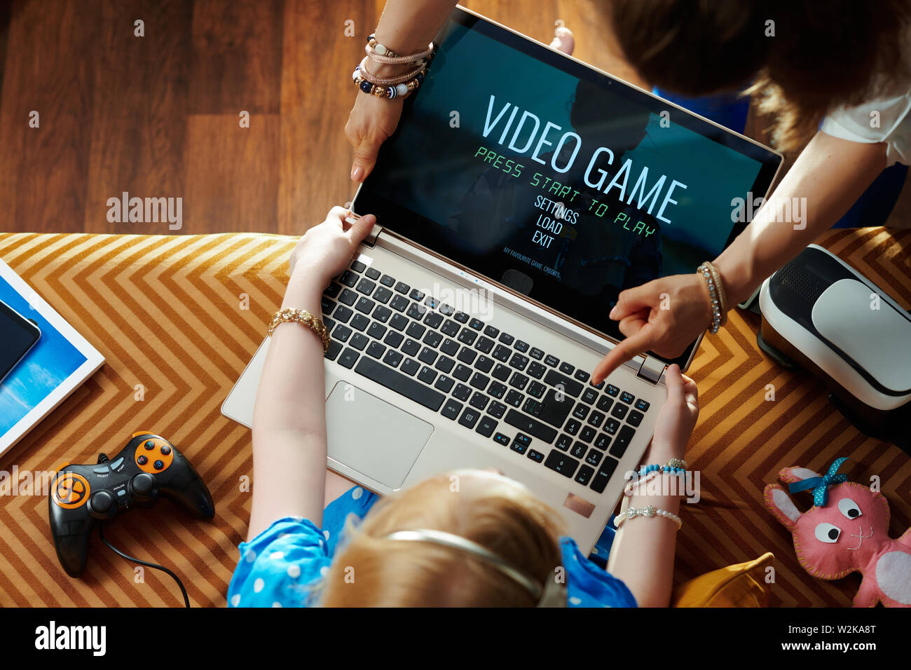 modern mother taking a laptop from addicted to video games sitting on sofa child in the modern living room Stock Photo