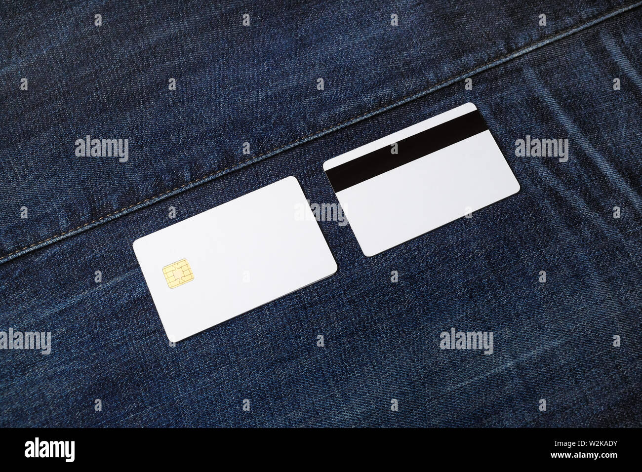 Two white blank credit cards on denim background. Chip cards. Front and back view. Stock Photo