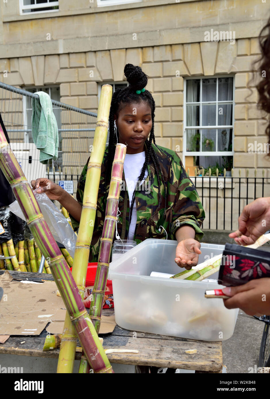 Young woman selling pieces of fresh sugar cane at Bristol St Paul's Carnival festival Stock Photo