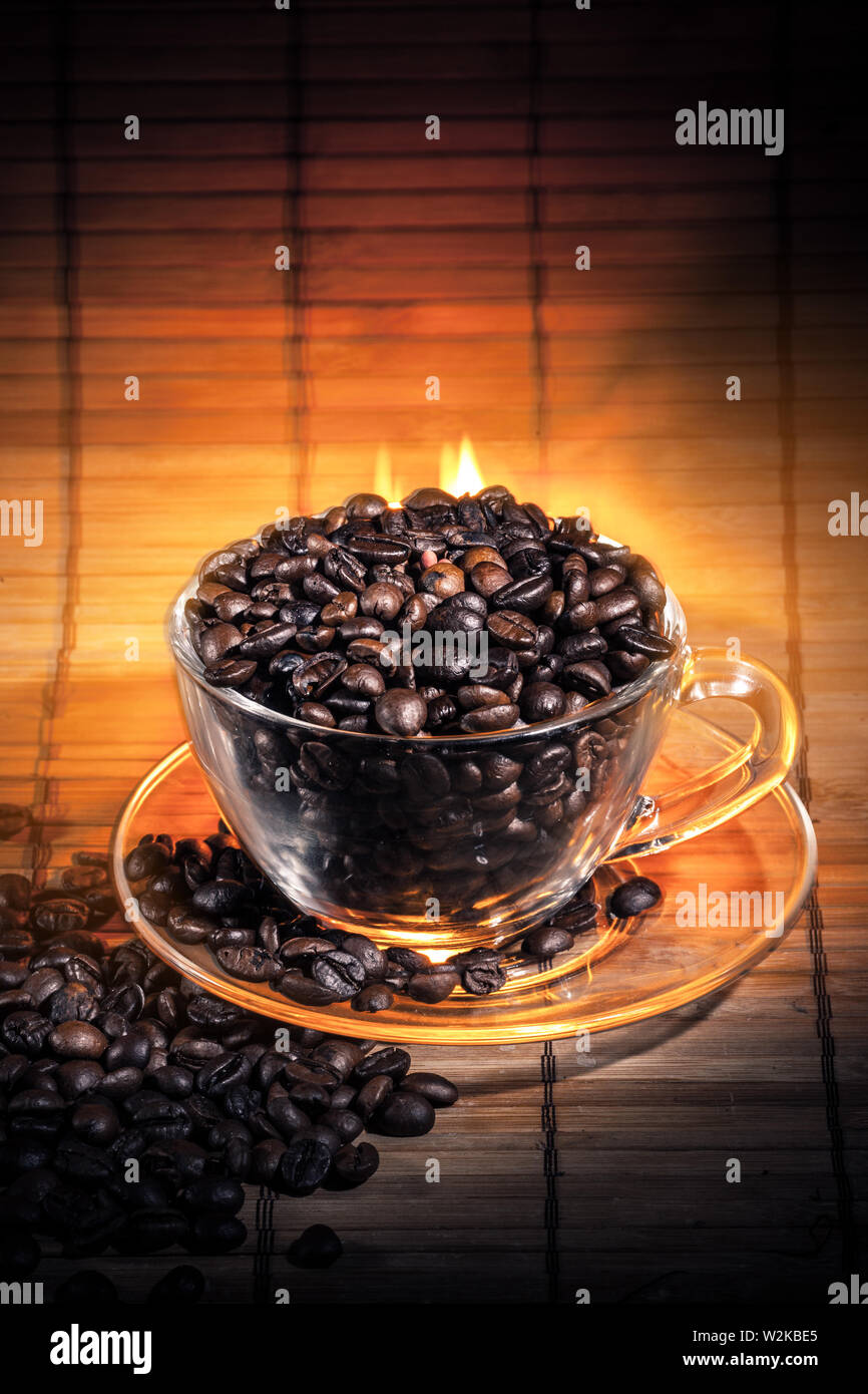 Steaming cup of coffee, cinnamon sticks and a coffee beans on fire Stock Photo