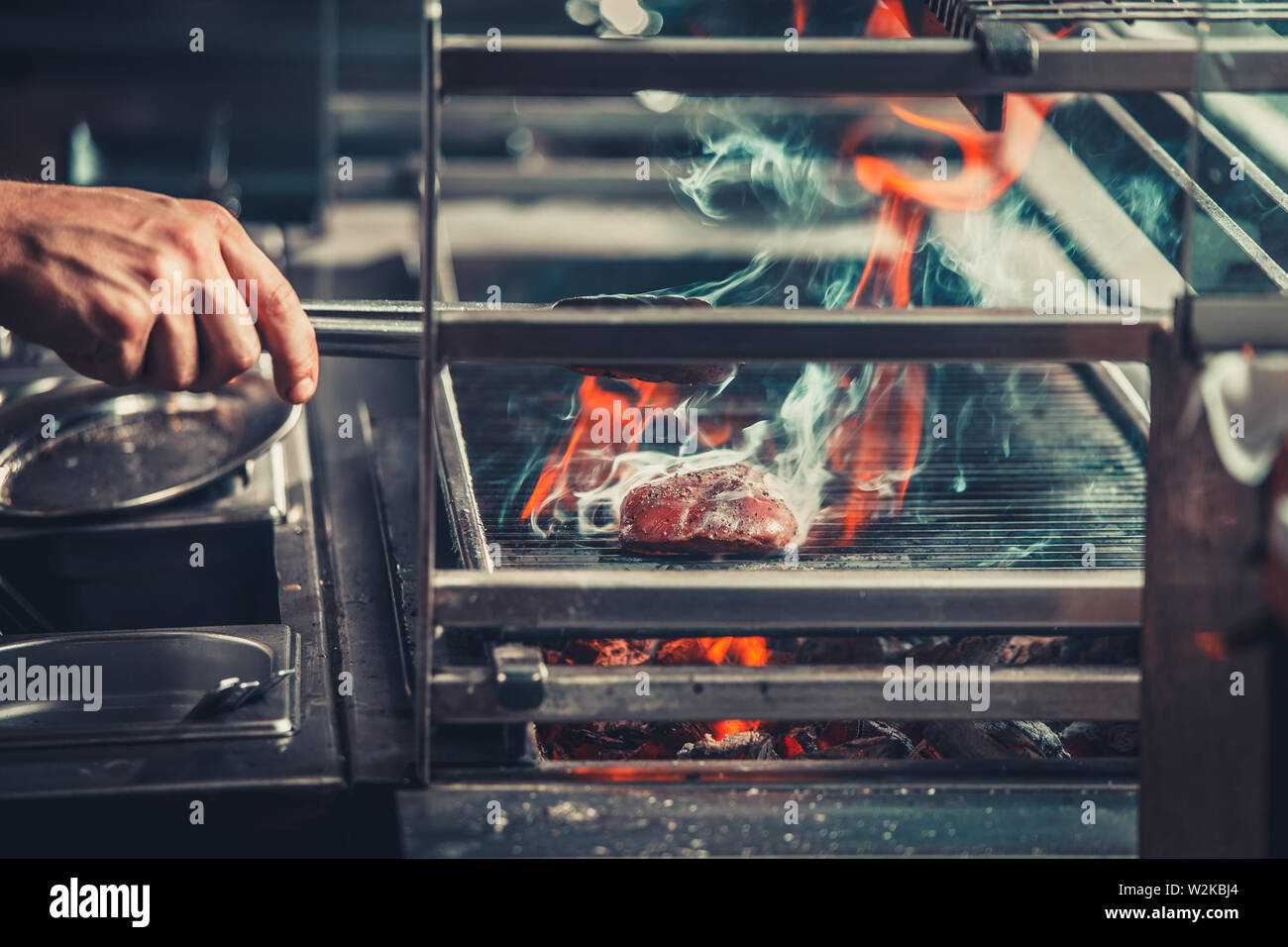 young male cooks preparing meal on the grill Stock Photo