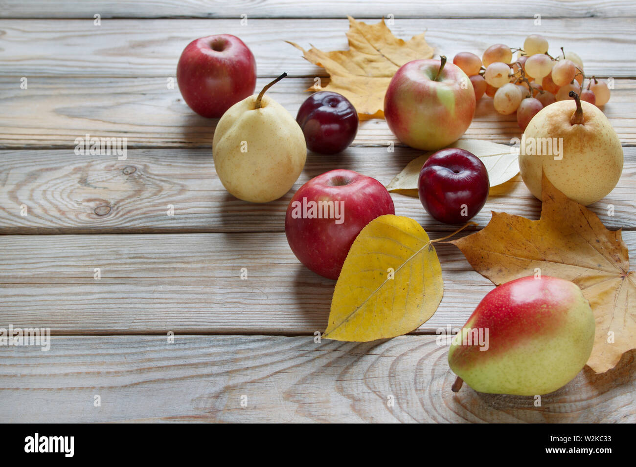 Autumn still life with various fruits are lying on a wooden desk ...