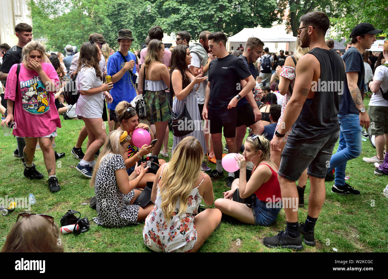 People all ages sitting, standing “hanging about” at summer Bristol St Pauls  Carnival festival, Brunswick Square, UK Stock Photo