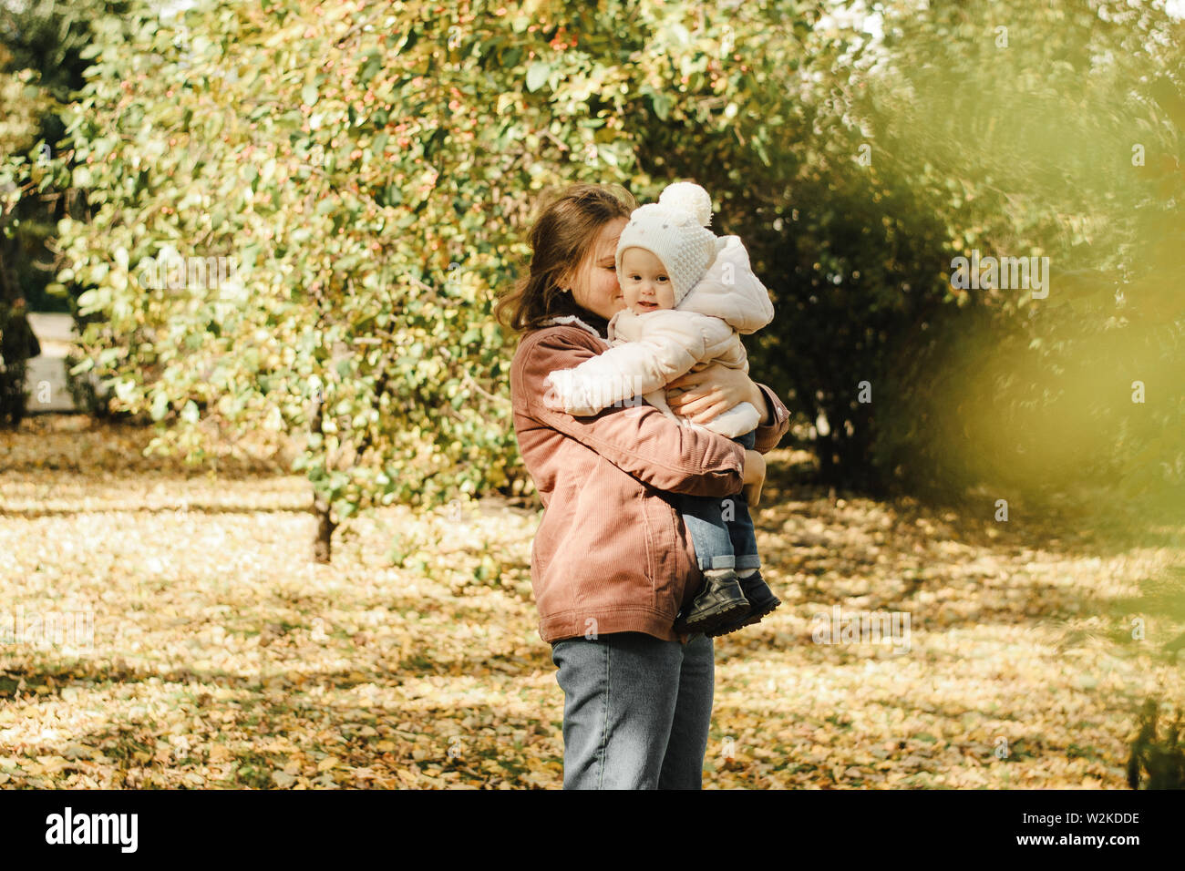 Cute, young mother throws her baby in the autumn park. Mom and daughter ...