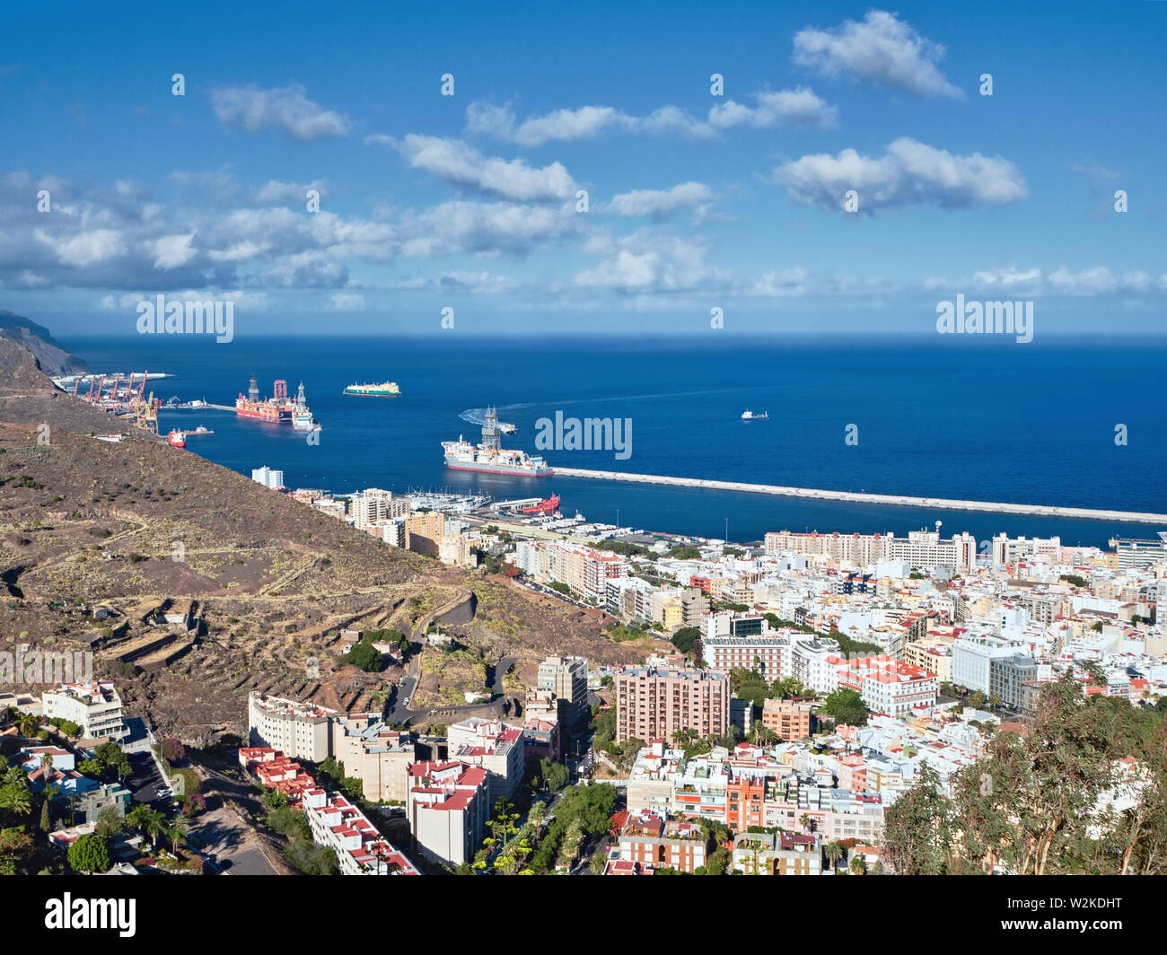 Port entrance of Santa Cruz de Tenerife photographed from high above. Dark blue Atlantic Ocean and sky with white clouds, a partial view of the white Stock Photo