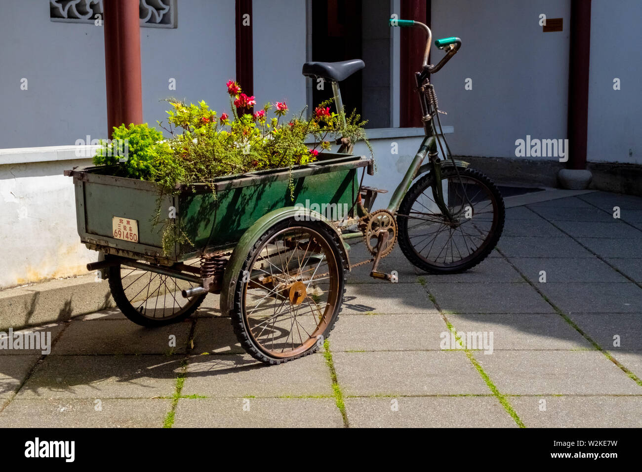 Ancient Tricycle with a Large Green Basket Full of Plants and Flowers at Dr. Sun Yat-Sen Classical Chinese Garden in Chinatown Vancouver BC Canada Stock Photo