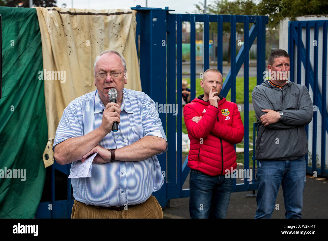 (Left to right) Orange Order grand secretary Mervyn Gibson, Jamie Bryson and Robert Girvin of the East Belfast Cultural Collective and, addressing supporters of the 11th Night bonfire at Avoniel Leisure Centre in Belfast, Northern Ireland, who have gathered together to mark the anniversary of the Battle of the Boyne. Stock Photo