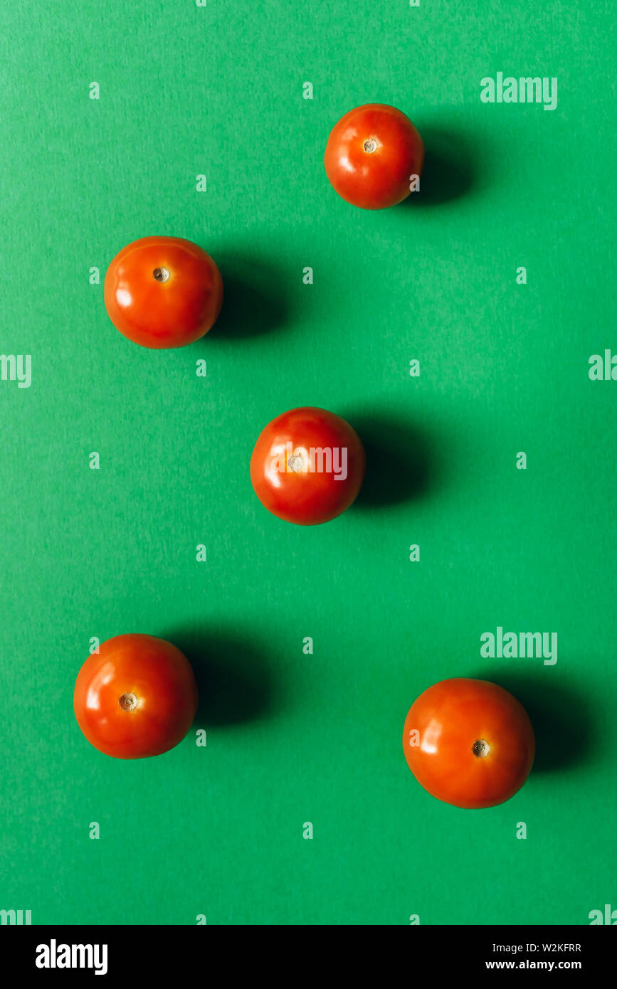 Five cherry tomatoes on a green background. Stock Photo