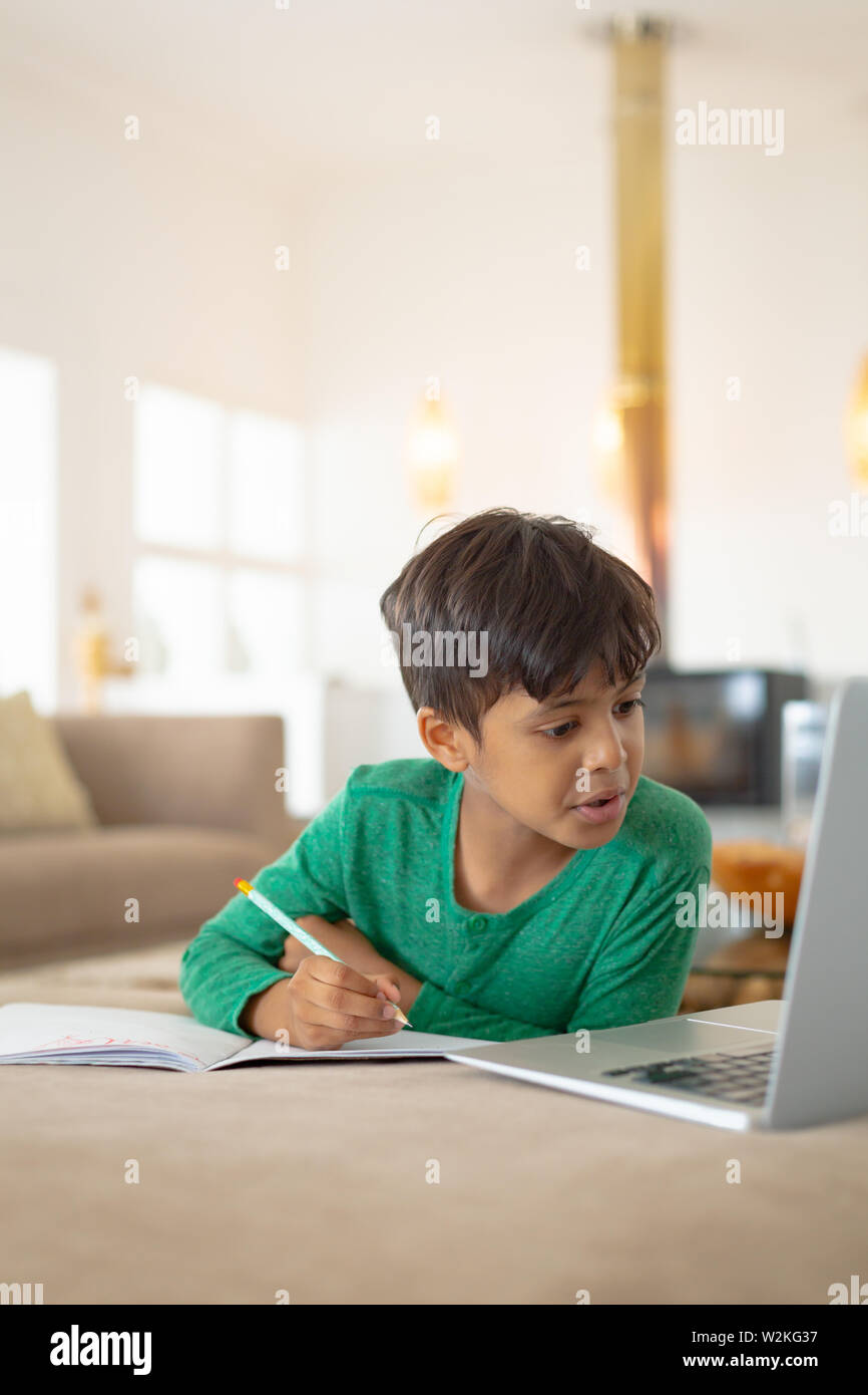 Boy using laptop while drawing a sketch on book at home Stock Photo