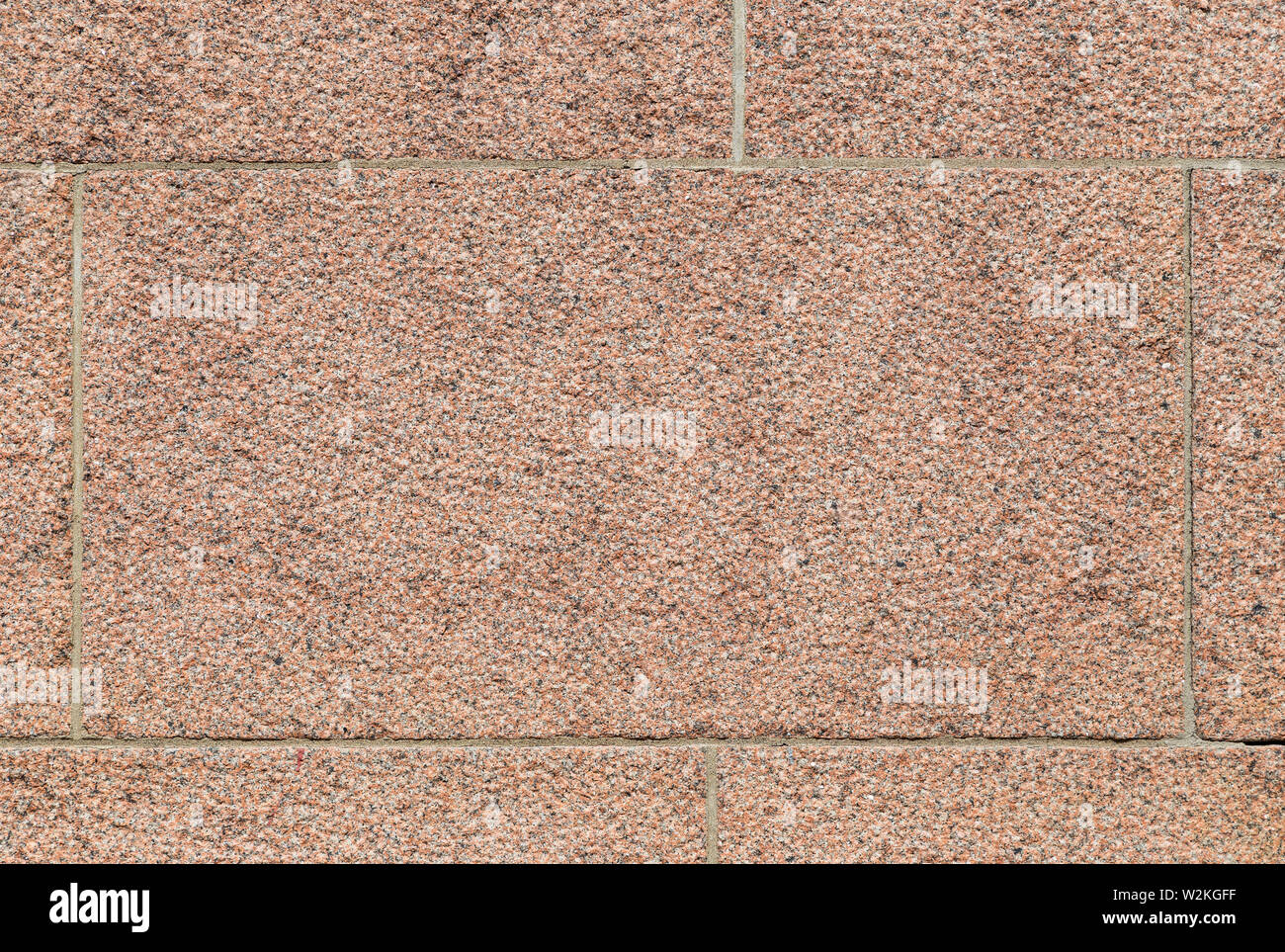 Close-up of part of a bumpy red granite block stone wall. High resolution full frame background texture. Stock Photo