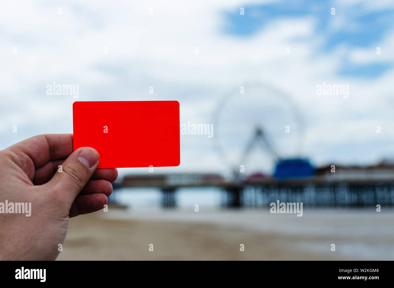 Coral plastic bank card with no credentials hold in hand. Mock up, copy space design template. Taken at sea coast Blackpool, United Kingdom Stock Photo